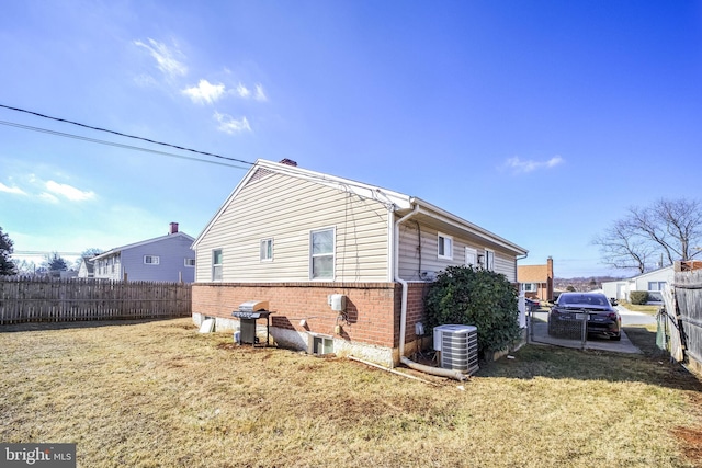 view of property exterior with a yard, brick siding, cooling unit, and fence