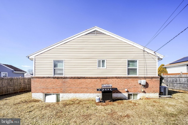 rear view of house featuring brick siding, a fenced backyard, and central air condition unit