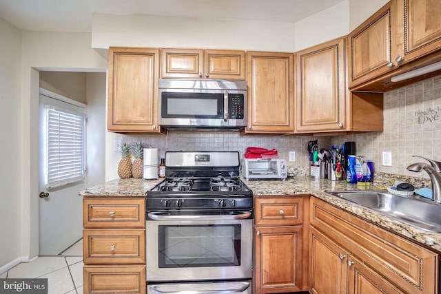 kitchen featuring light tile patterned floors, backsplash, stainless steel appliances, and a sink