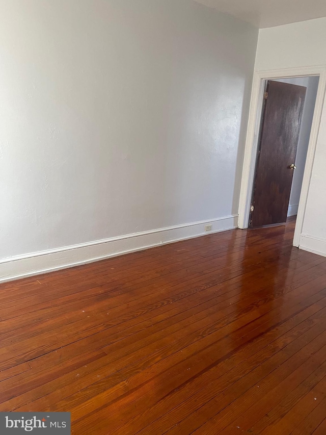 spare room with dark wood finished floors and baseboards