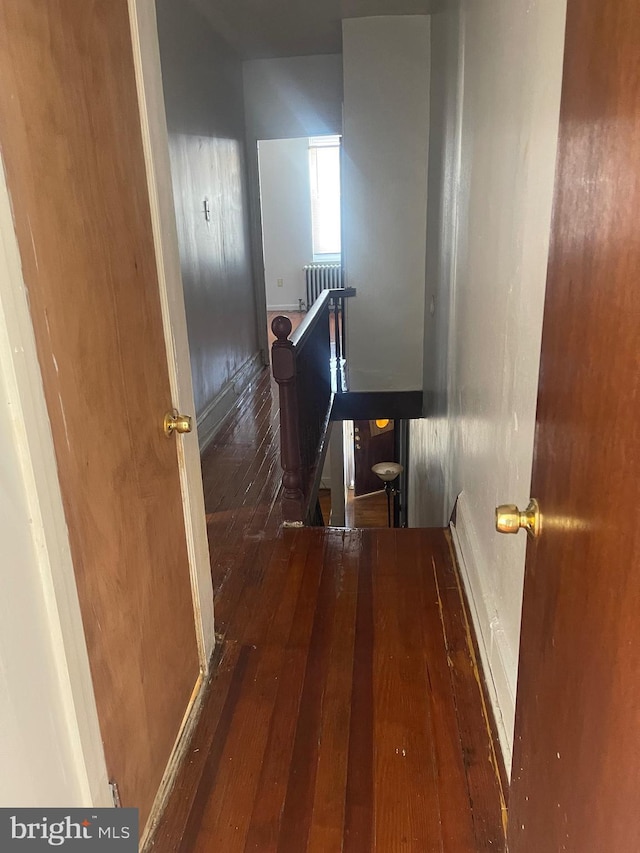 hallway featuring radiator, hardwood / wood-style floors, and an upstairs landing