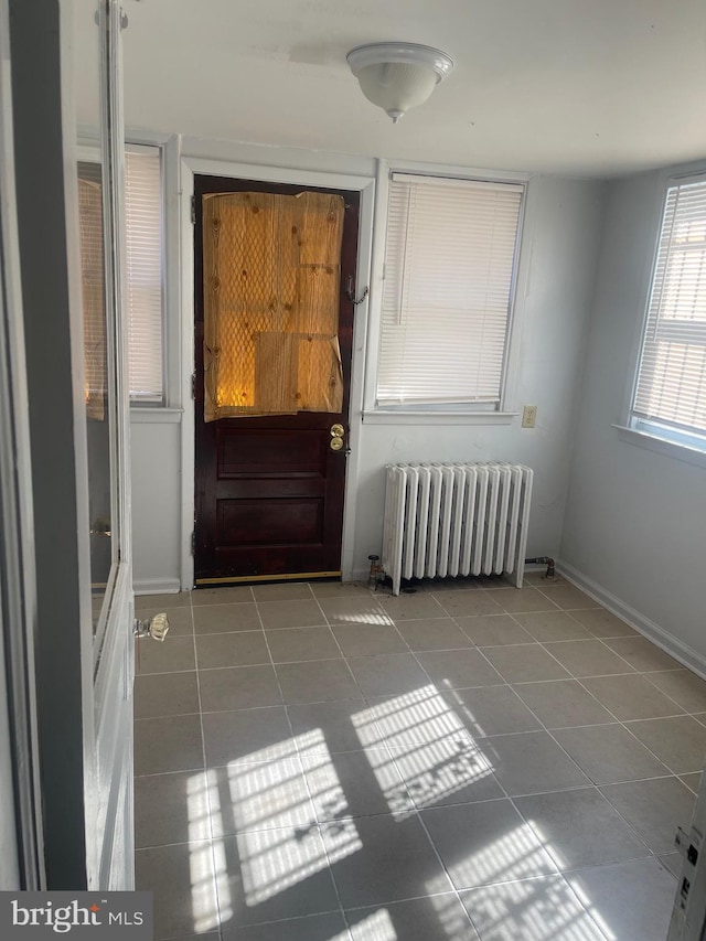 doorway to outside featuring radiator heating unit, tile patterned flooring, and baseboards