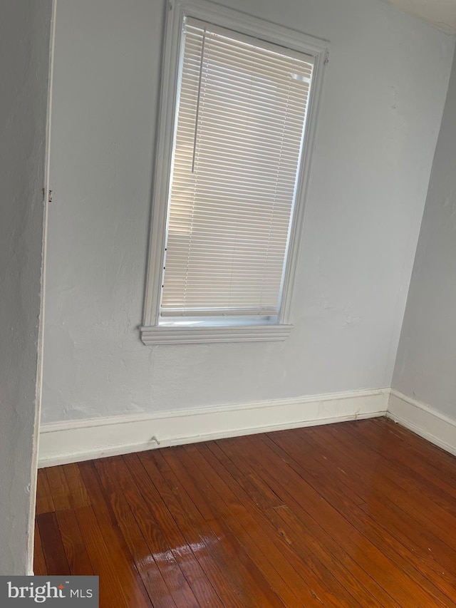 unfurnished room with wood-type flooring and baseboards