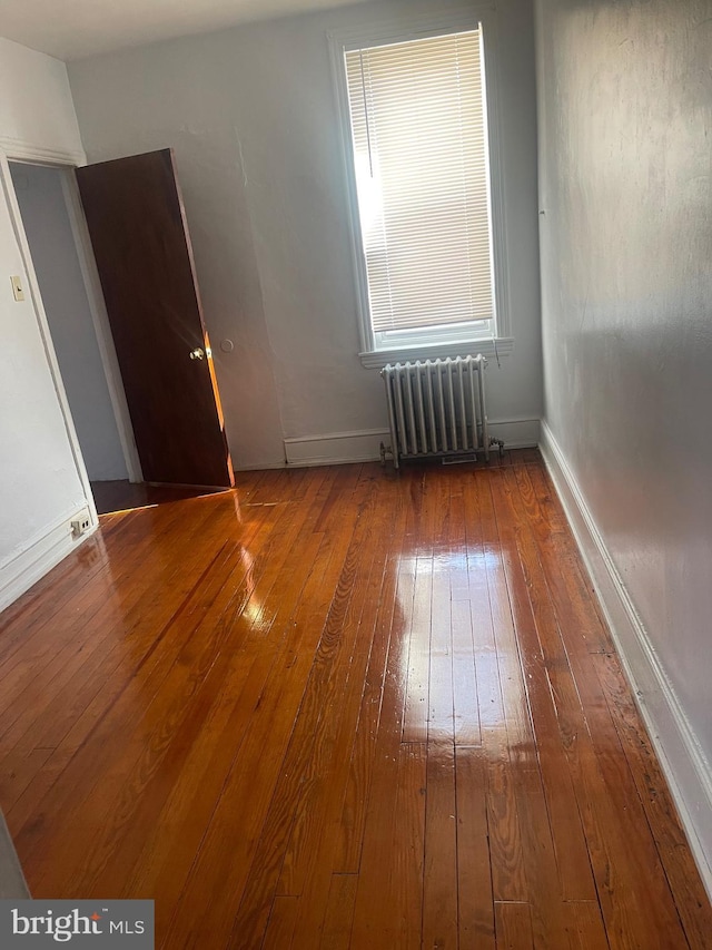 unfurnished room with radiator, baseboards, and hardwood / wood-style floors