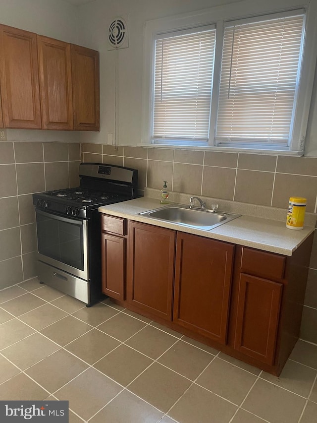 kitchen featuring light countertops, brown cabinets, a sink, and gas range