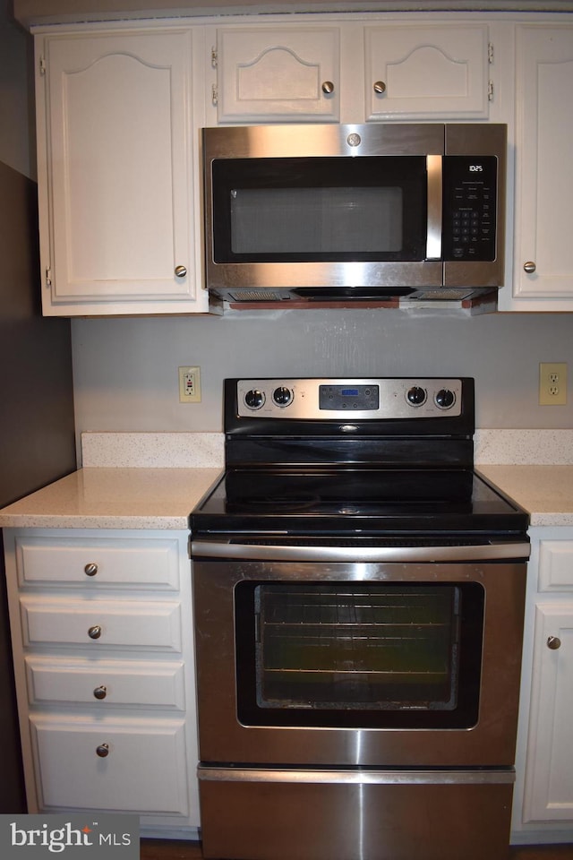 kitchen with stainless steel appliances, light countertops, and white cabinets