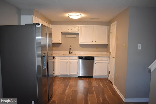 kitchen featuring dark wood-style floors, stainless steel appliances, light countertops, white cabinetry, and a sink