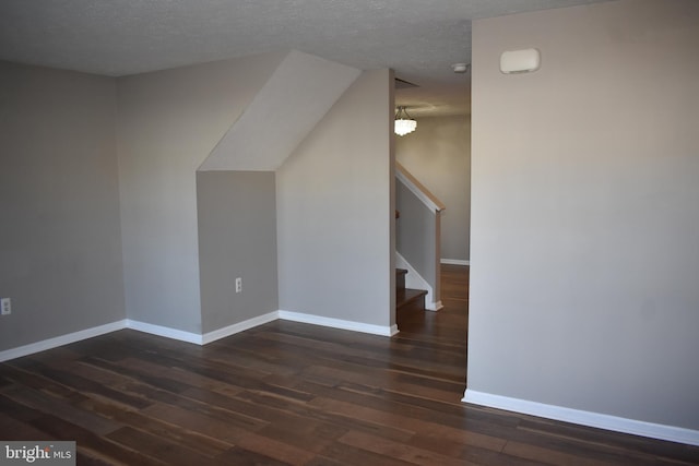 bonus room featuring a textured ceiling, stairway, wood finished floors, and baseboards