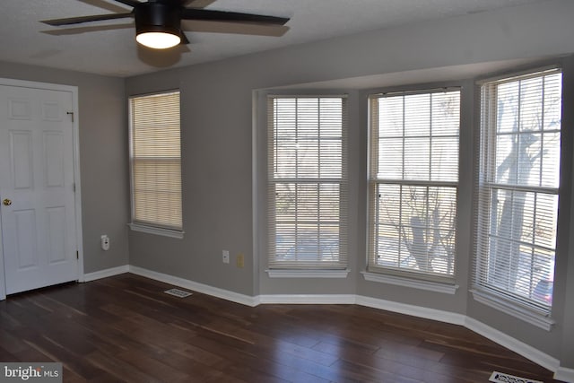 interior space featuring dark wood-style floors, visible vents, baseboards, and a ceiling fan