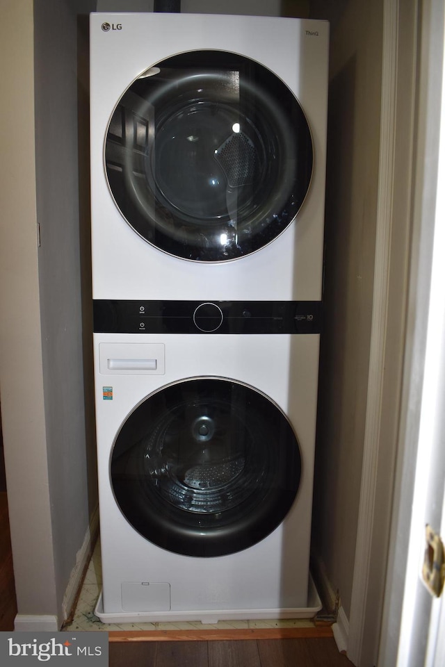 clothes washing area with laundry area, stacked washer / dryer, and baseboards