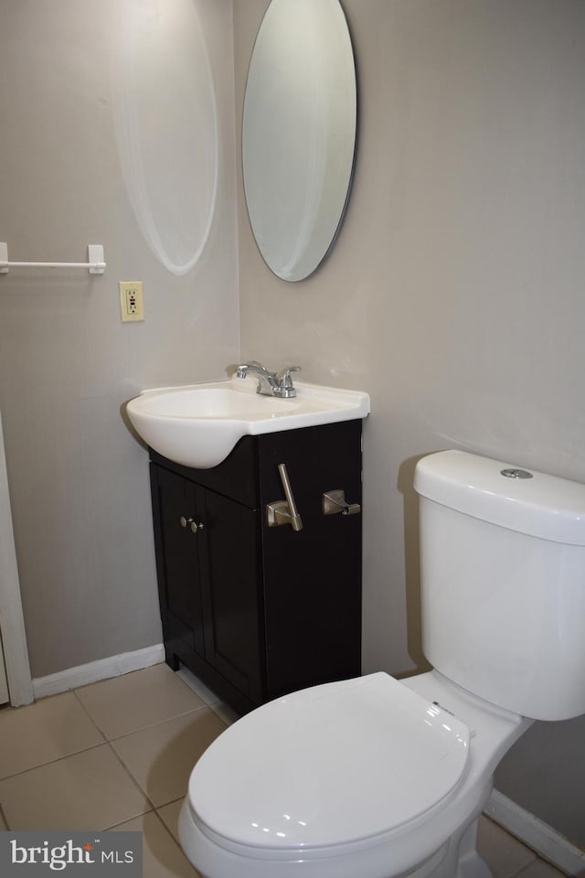 half bathroom featuring baseboards, vanity, toilet, and tile patterned floors