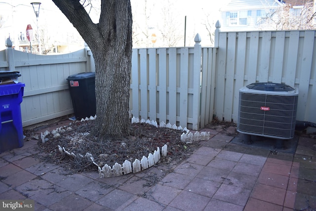 exterior space with central air condition unit, a fenced backyard, and a patio