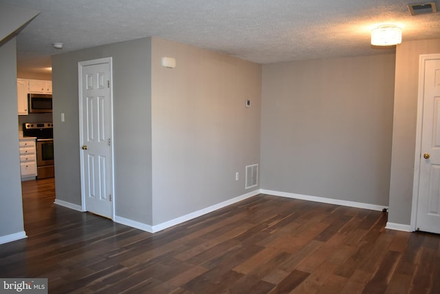 spare room featuring dark wood-type flooring, visible vents, and baseboards