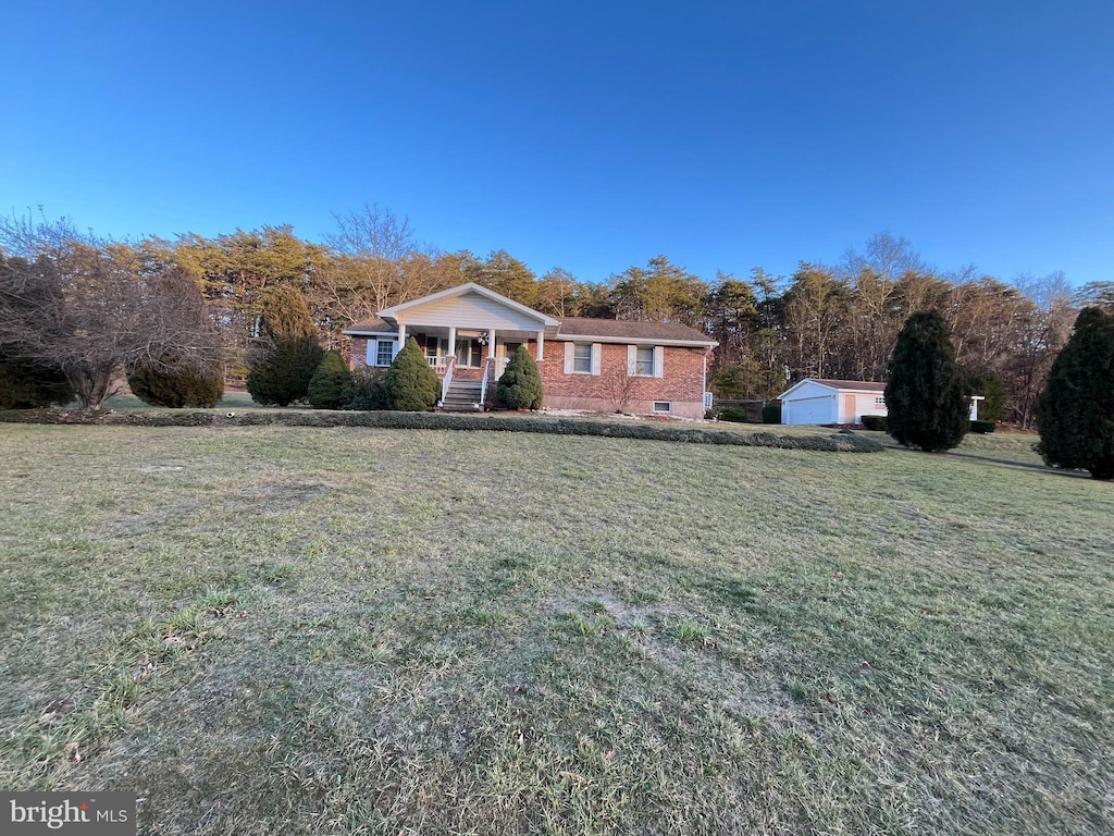 view of front of house featuring covered porch, crawl space, a front yard, and an outdoor structure