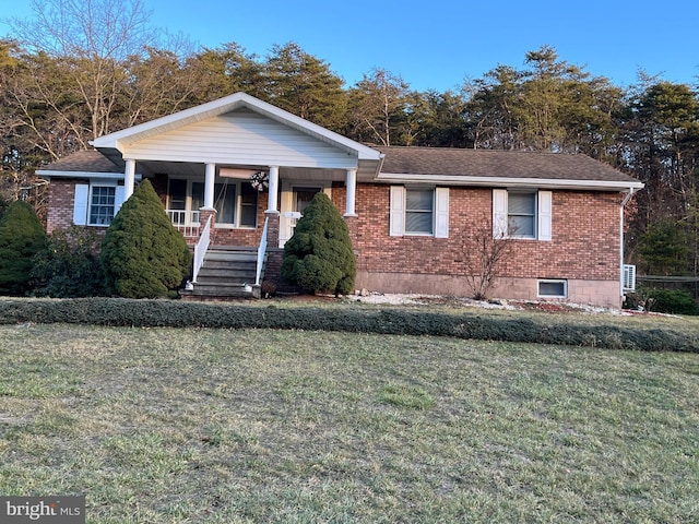 view of front of home with brick siding, a porch, a front yard, and a shingled roof