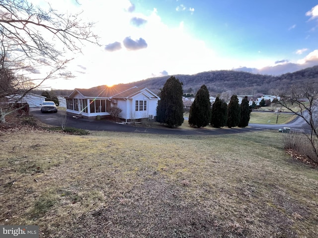 exterior space with a sunroom, a mountain view, and a lawn