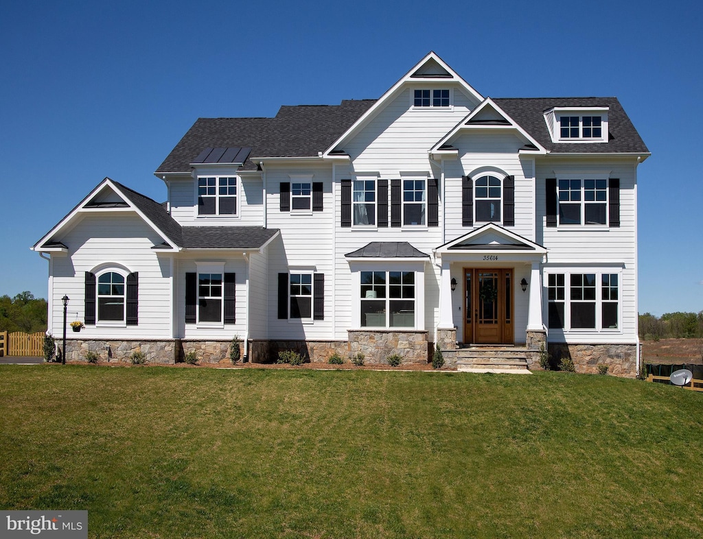 view of front of property featuring a front lawn and roof with shingles