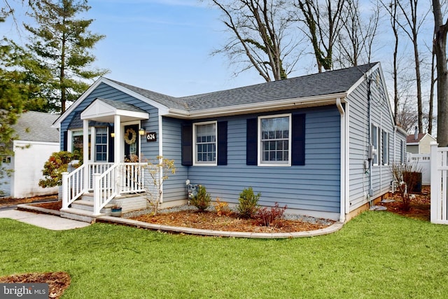 view of front facade featuring a front lawn, roof with shingles, and fence