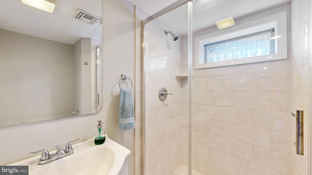 full bath featuring a stall shower, a sink, and visible vents