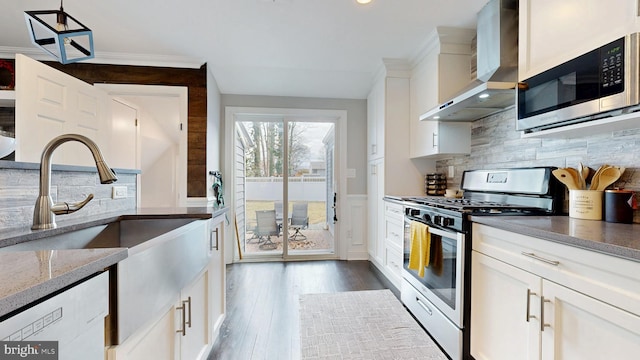 kitchen featuring dark wood-style flooring, backsplash, appliances with stainless steel finishes, white cabinetry, and wall chimney exhaust hood