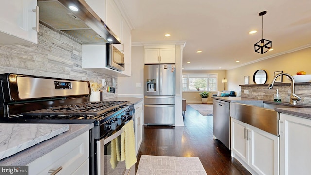 kitchen with stainless steel appliances, a sink, white cabinetry, wall chimney exhaust hood, and crown molding