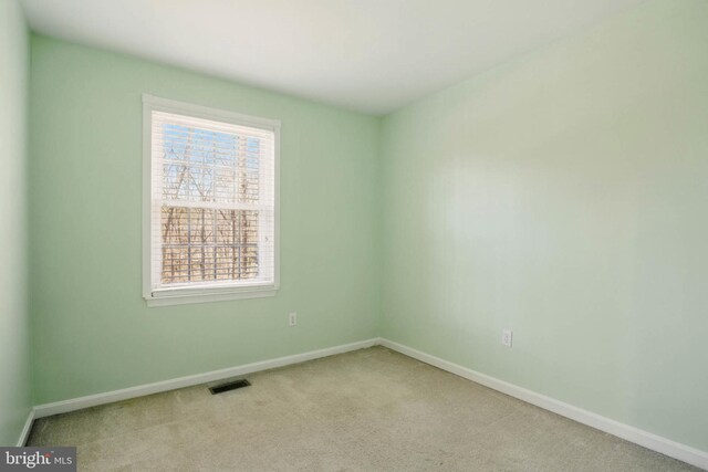 spare room featuring carpet flooring, visible vents, and baseboards