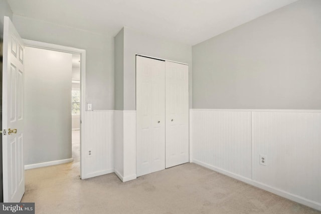 unfurnished bedroom with carpet flooring, a closet, and wainscoting