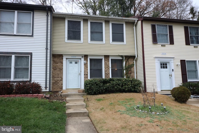 townhome / multi-family property with a front lawn and brick siding