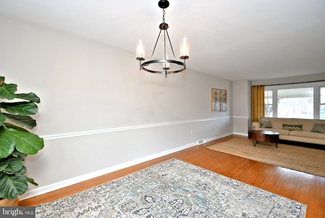 interior space featuring an inviting chandelier, wood finished floors, and baseboards