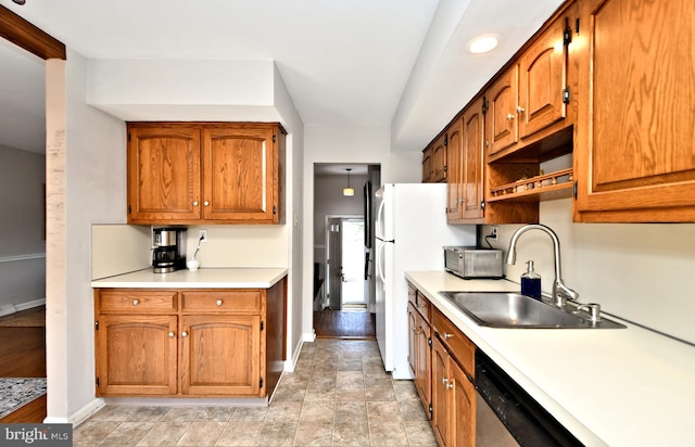 kitchen with stainless steel dishwasher, light countertops, a sink, and brown cabinetry