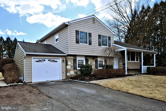 tri-level home featuring an attached garage, stone siding, driveway, and a shingled roof