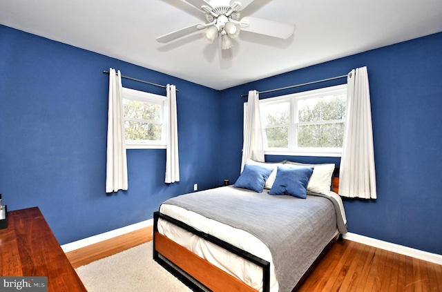 bedroom with wood finished floors, a ceiling fan, and baseboards