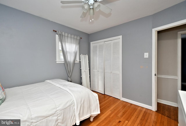 bedroom with a ceiling fan, a closet, hardwood / wood-style flooring, and baseboards