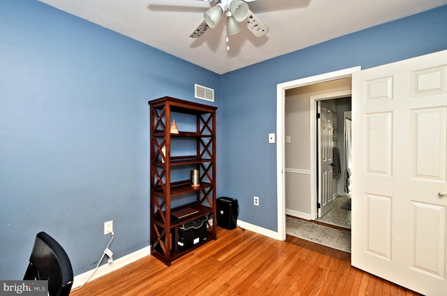 unfurnished office featuring baseboards, visible vents, ceiling fan, and hardwood / wood-style floors