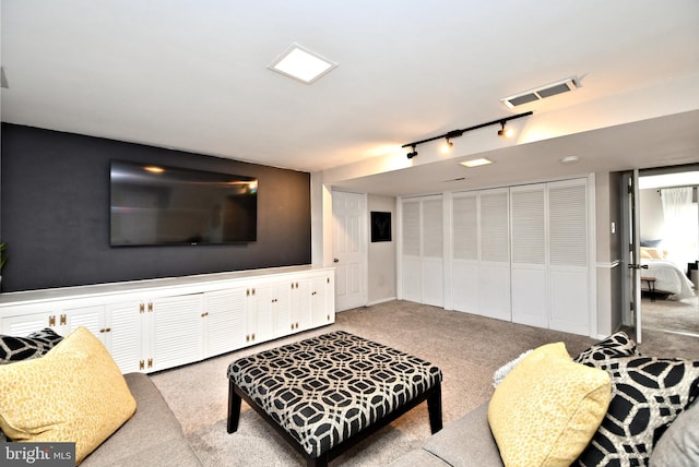 living area featuring carpet floors, visible vents, and track lighting