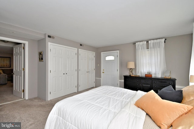 carpeted bedroom featuring visible vents and multiple closets