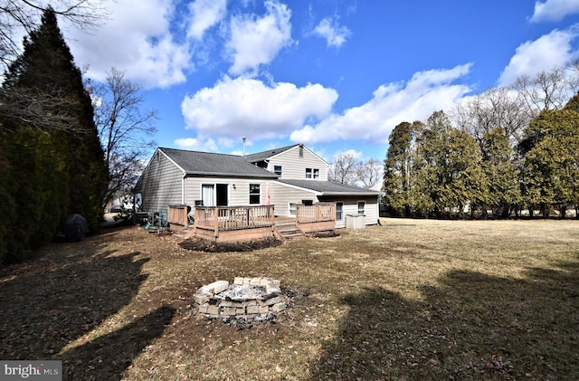 back of property featuring a deck, a yard, and a fire pit