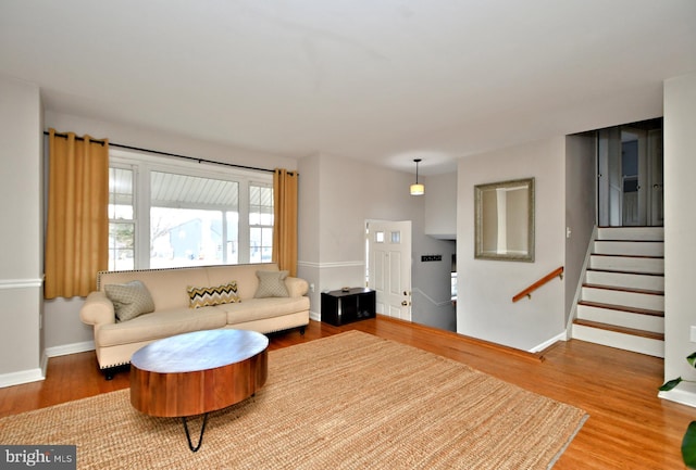 living area with stairs, baseboards, and wood finished floors