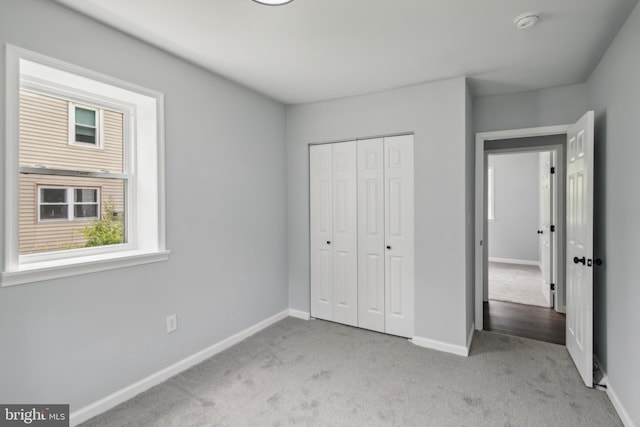 unfurnished bedroom featuring carpet floors, baseboards, and a closet