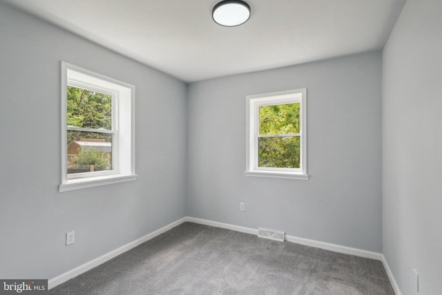 carpeted spare room featuring visible vents and baseboards