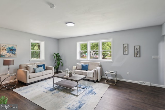 living room with wood finished floors, visible vents, and baseboards