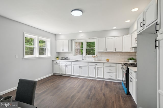 kitchen featuring stainless steel gas range oven, tasteful backsplash, dark wood finished floors, light countertops, and white cabinetry