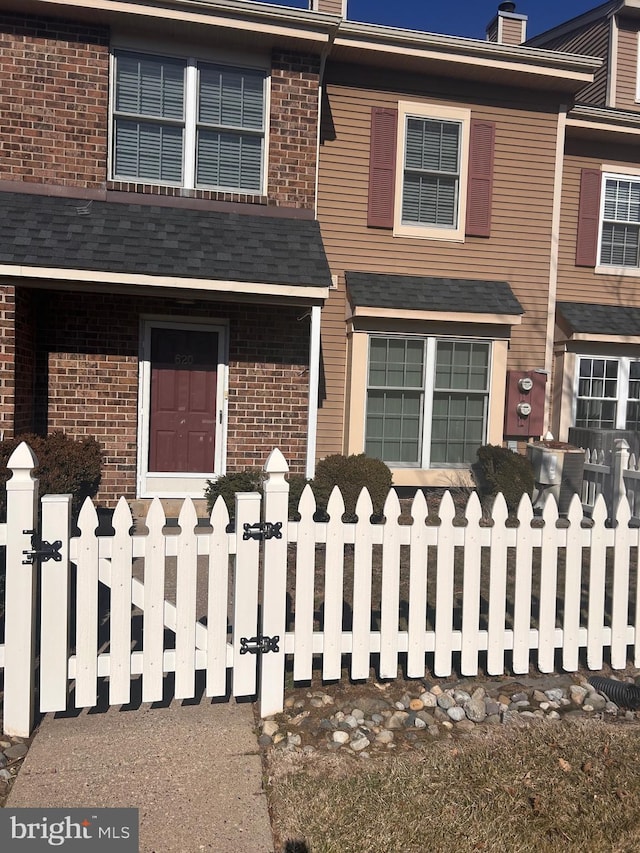 multi unit property featuring a fenced front yard, a chimney, and brick siding