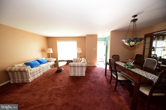 living room with a healthy amount of sunlight, dark carpet, and baseboards