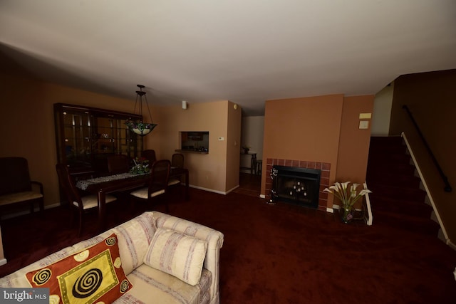 living room with baseboards, a tiled fireplace, and stairs