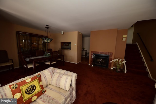 living area with baseboards, stairway, and a tiled fireplace