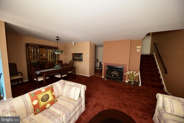 carpeted living room with stairs, baseboards, and a tile fireplace