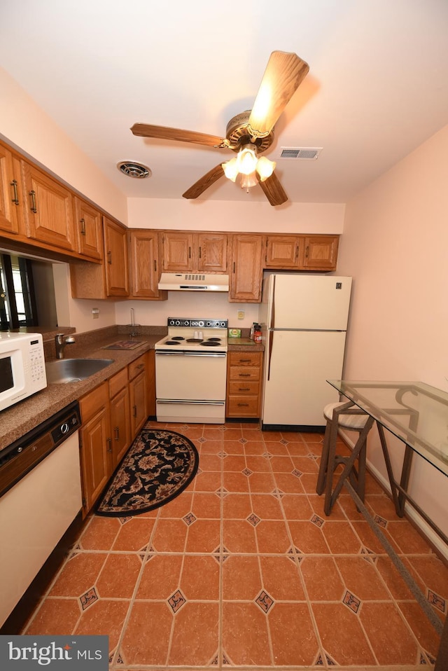 kitchen featuring white appliances, under cabinet range hood, visible vents, and a sink