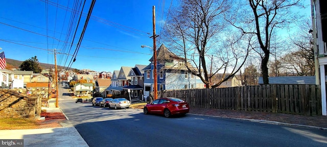 view of street featuring a residential view, curbs, street lights, and sidewalks