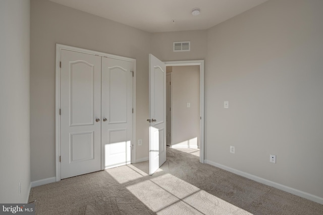 unfurnished bedroom with a closet, carpet, visible vents, and baseboards